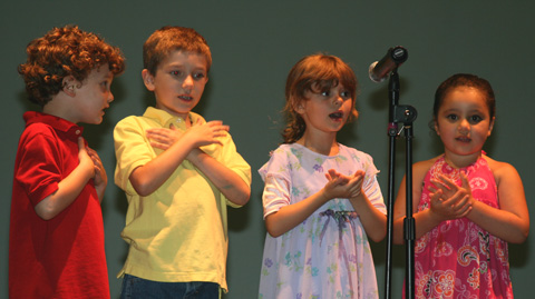 Four children singing in front of a microphone